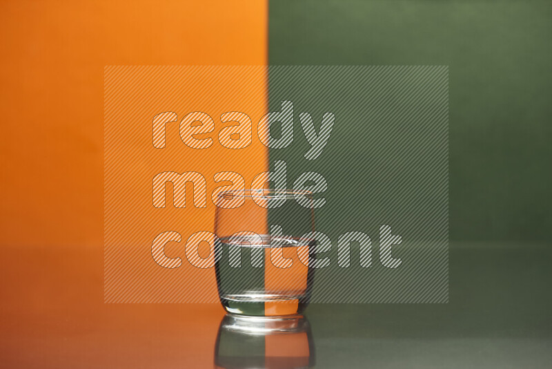 The image features a clear glassware filled with water, set against orange and dark green background