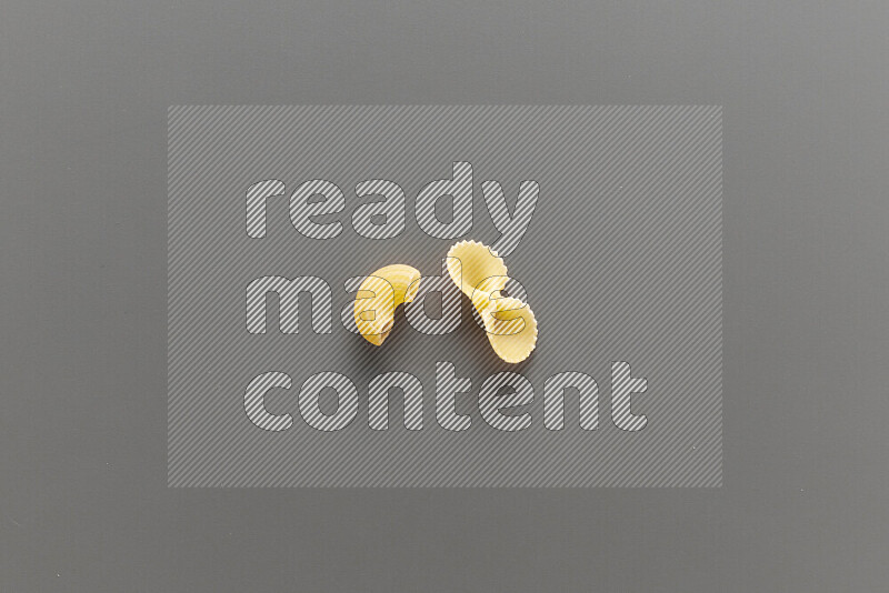 Elbow pasta with other types of pasta on grey background