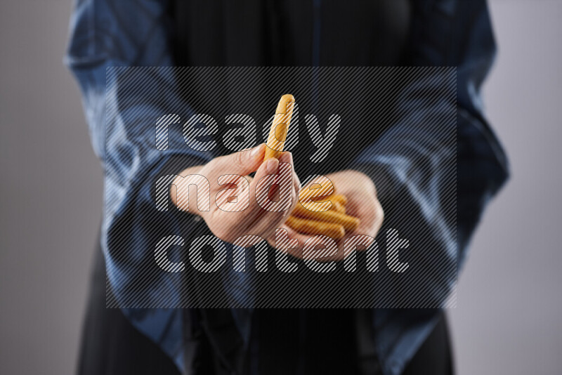 Woman in abaya holding different kinds of snacks in different positions