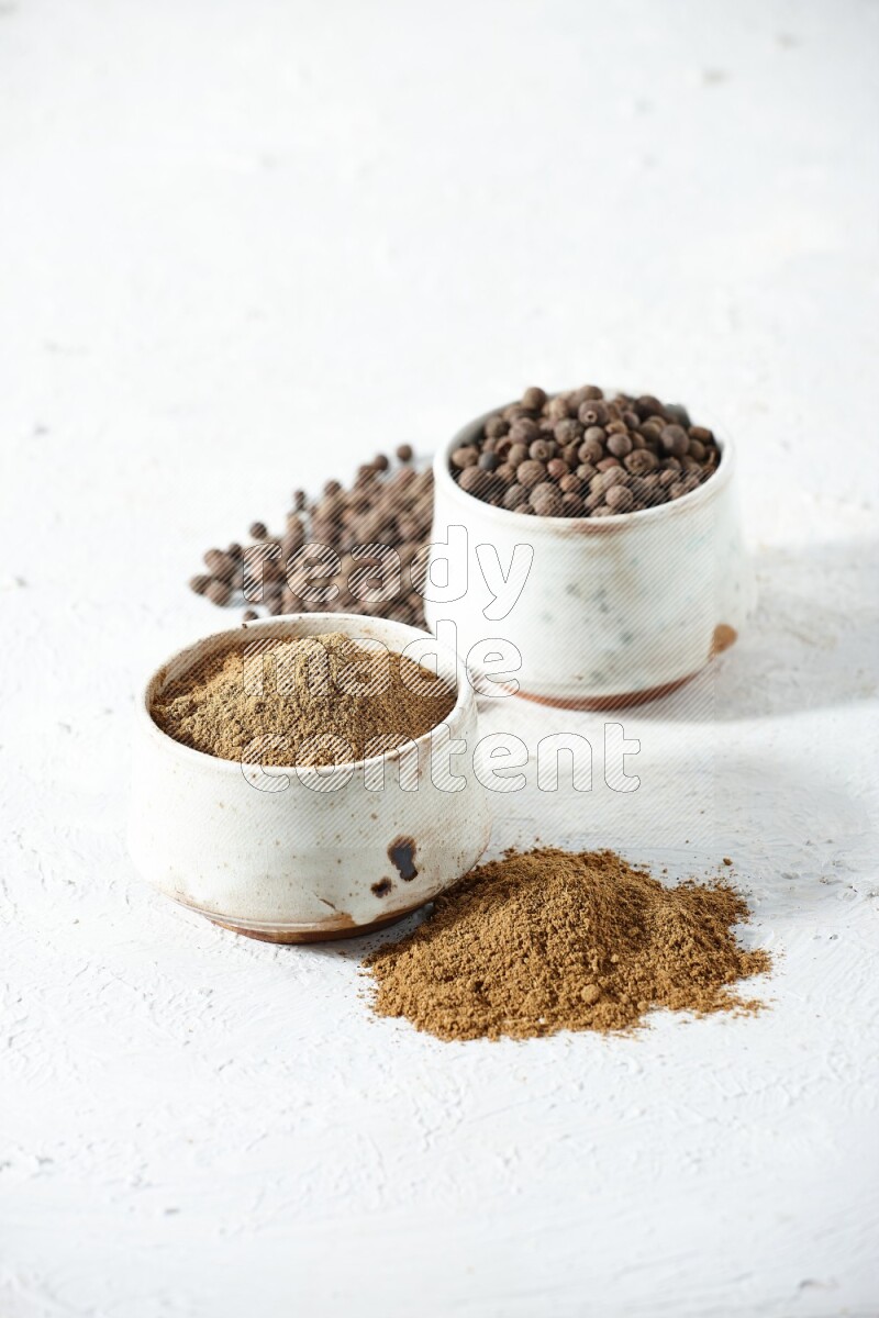 وعاءان بيج، أحدهما ممتلئ ببودرة بهار الفلفل الحلو والآخر بالحبوب مع البودرة والحبوب متناثرة على خلفية بيضاء