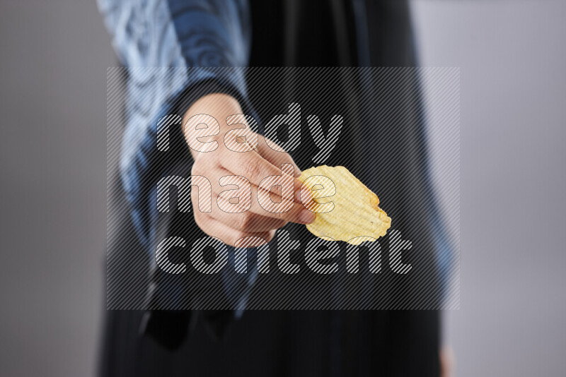 Woman in abaya holding different kinds of snacks in different positions