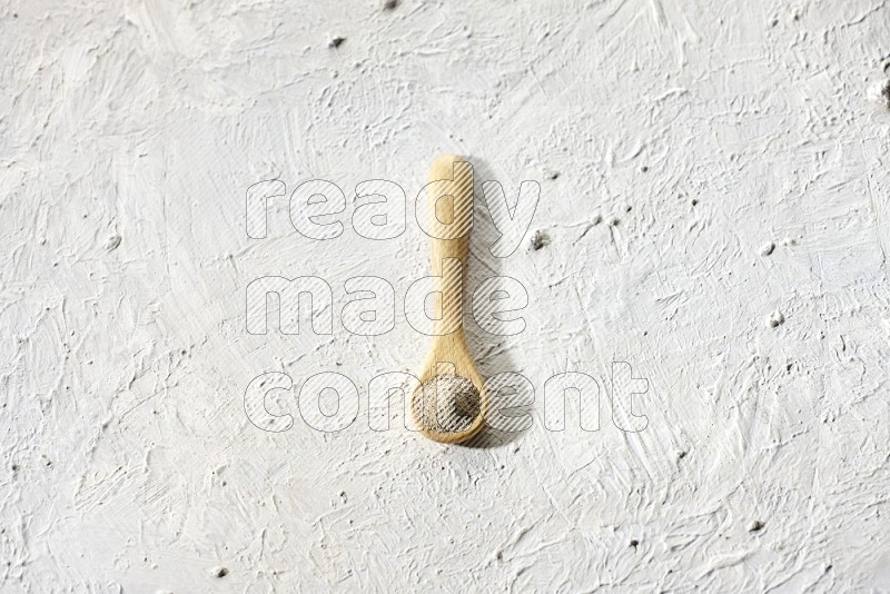 ملعقة خشبية مملوءة ببودرة الفلفل الأبيض على أرضية بيضاء