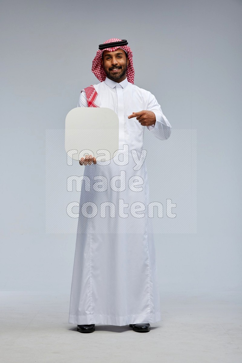 Saudi man Wearing Thob and shomag standing holding social media sign on Gray background