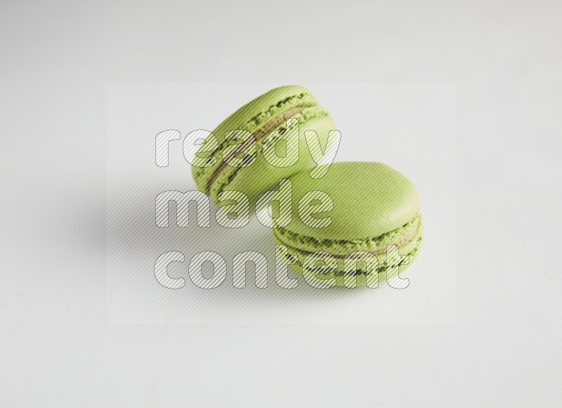 45º Shot of two Green Pistachio macarons on white background