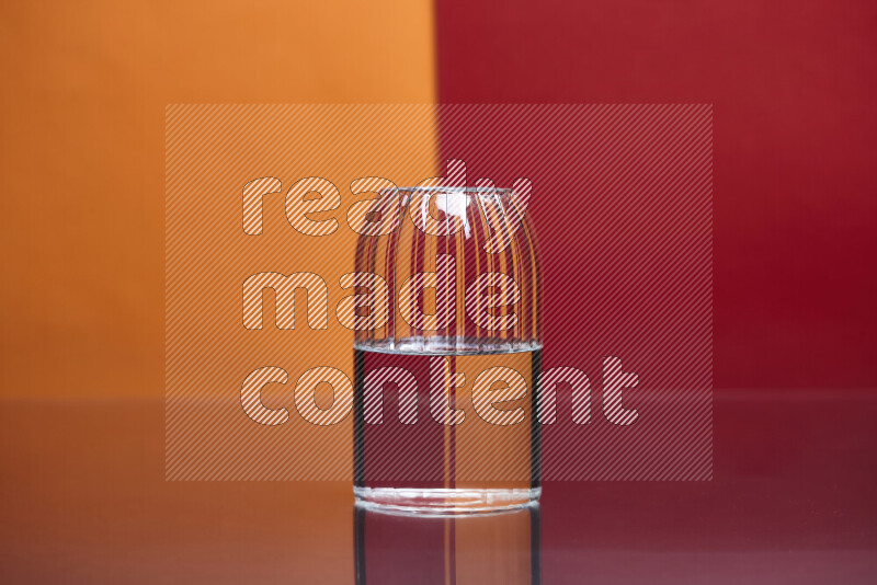 The image features a clear glassware filled with water, set against orange and red background