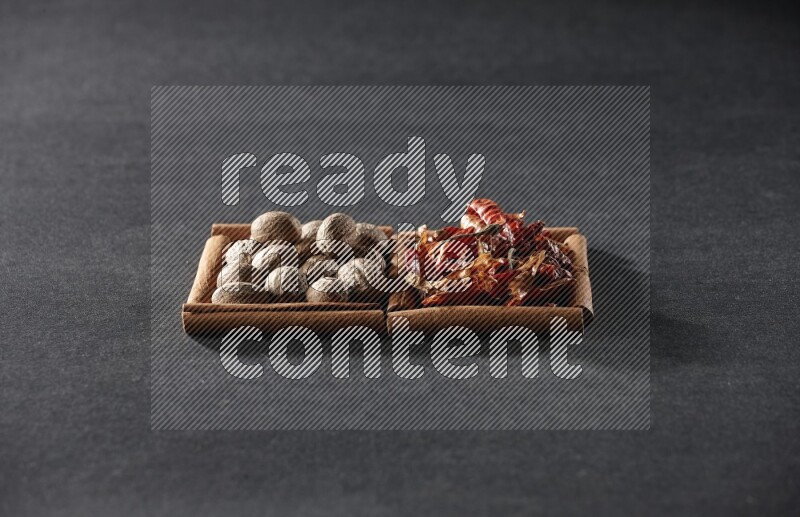 مربعان من أعواد القرفة ممتلئان بجوزة الطيب والفلفل الحار المجفف علي خلفية سوداء