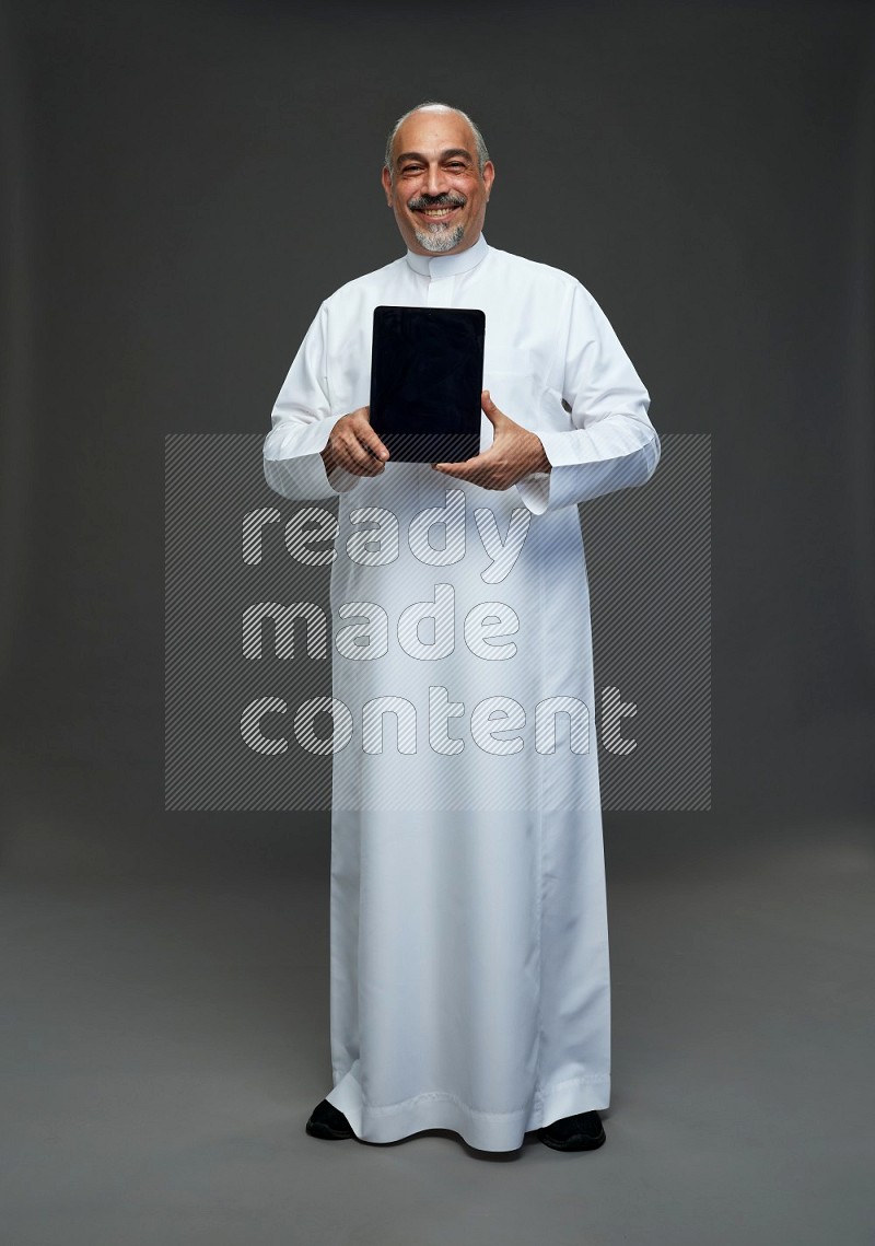 Saudi man without shomag Standing working on tablet on gray background