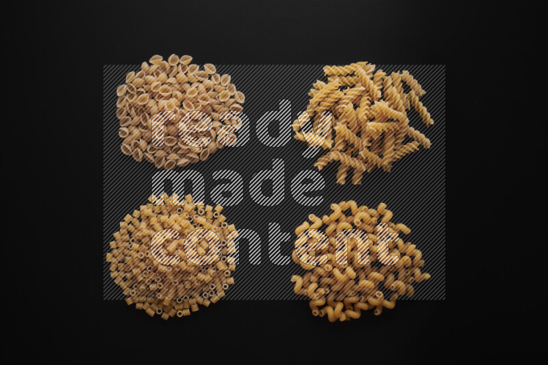 Different pasta types in bunches on black background