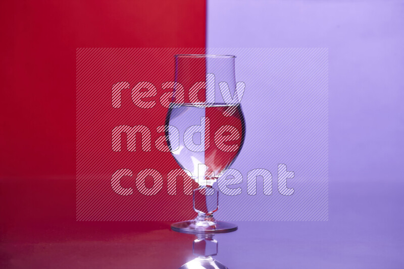 The image features a clear glassware filled with water, set against red and light purple background