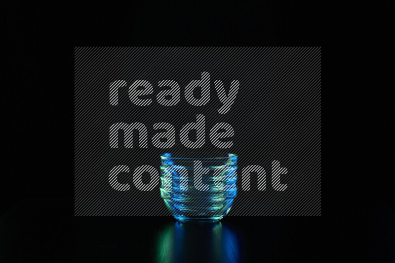 Glassware with rim light in blue and green against black background