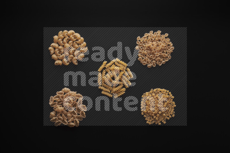 Different pasta types in bunches on black background