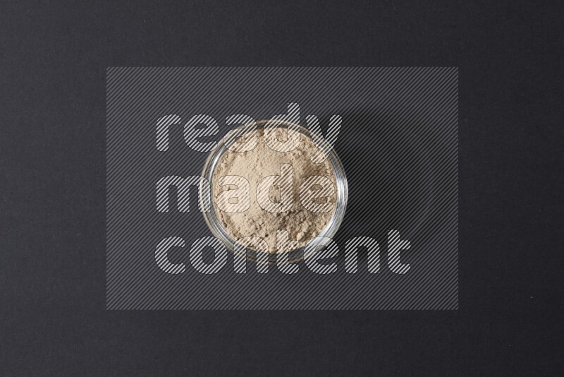 وعاء زجاجي ممتلئ ببودرة الثوم علي خلفية سوداء