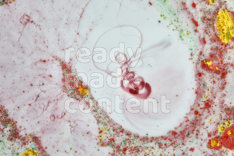 The image captures a splatter of yellow, red and green paint over a white backdrop