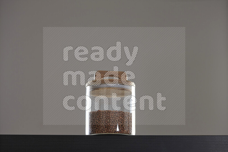 Brown lentils in a glass jar on black background