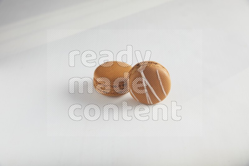 45º Shot of of two assorted Brown Irish Cream, and Brown Maple Taffy macarons  on white background