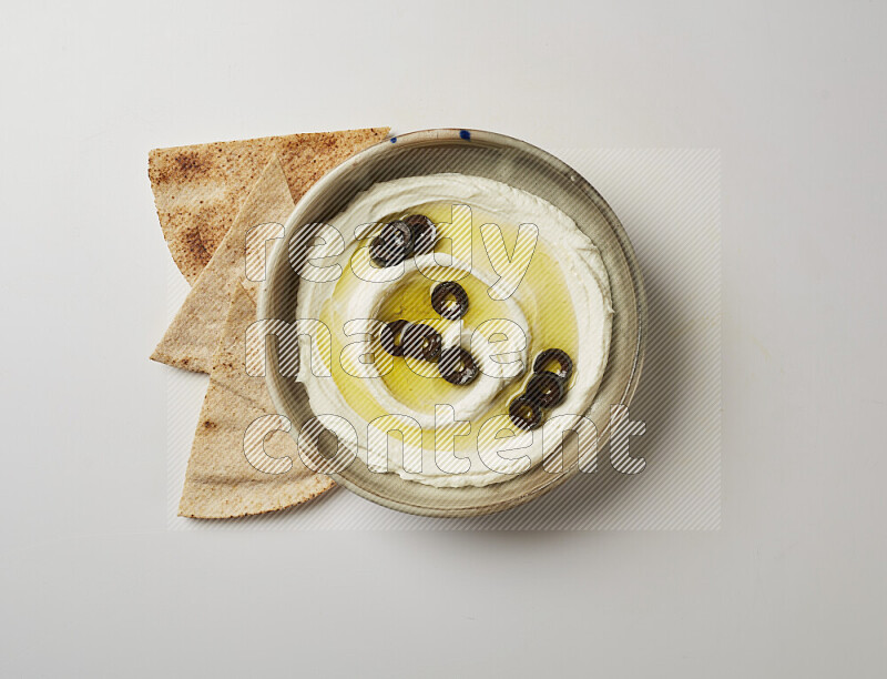 Lebnah garnished with sliced olives in a grey pottery plate on a white background