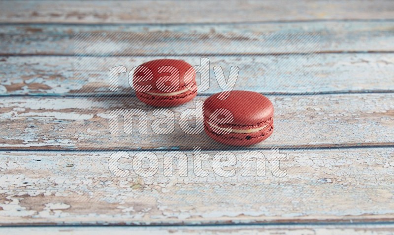 45º Shot of two Red Velvet macarons on light blue wooden background