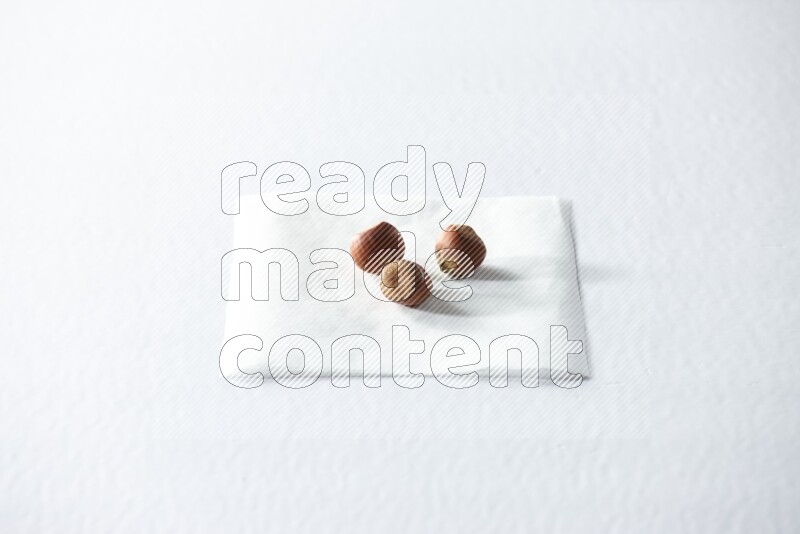 3 hazelnuts on a piece of paper on a white background in different angles