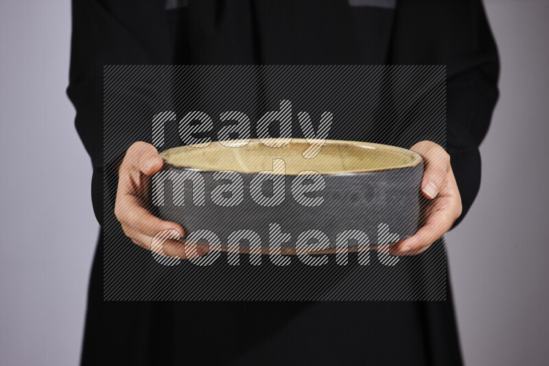 A woman in black abaya holding different pottery essentials in different positions