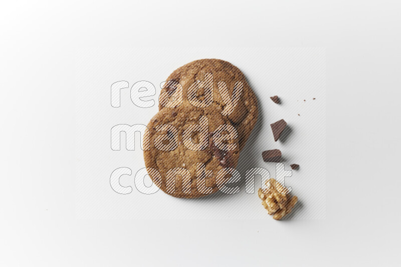 Chocolate chips cookies with chocolate and walnuts beside it on a white background