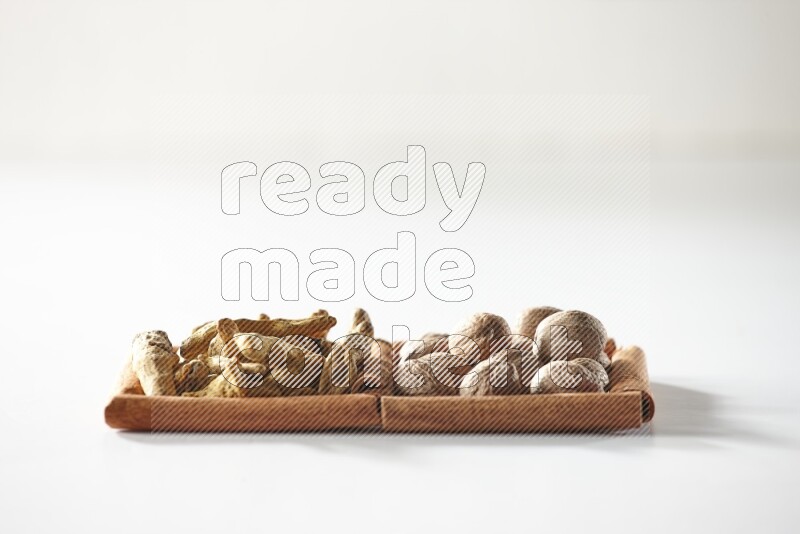 مربعان من أعواد القرفة ممتلئان بأصابع الكركم  وجوزة الطيب علي خلفية بيضاء