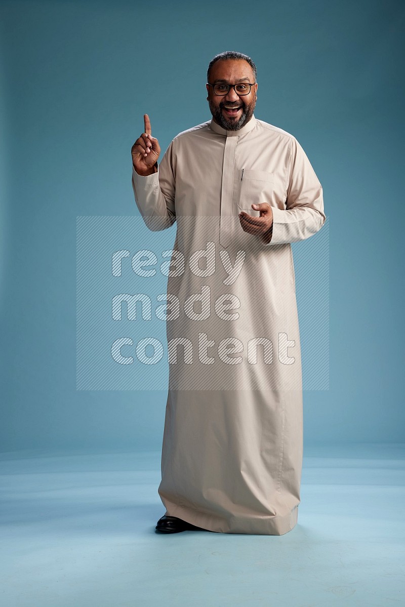 Saudi Man without shimag Standing Interacting with the camera on blue background