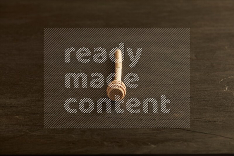 Wooden honey dipper on black slate background