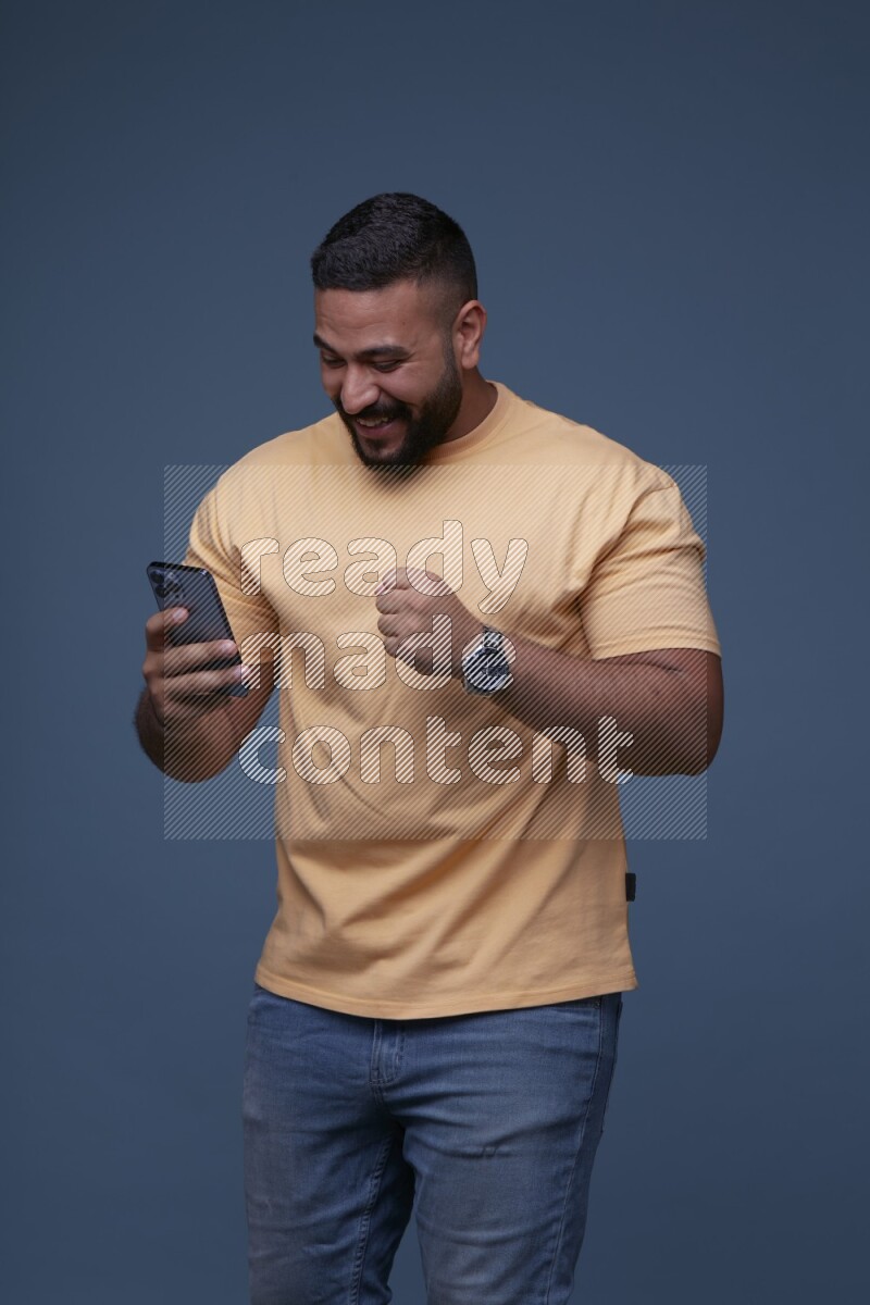 A man Texting on his phone on Blue Background wearing Orange T-shirt
