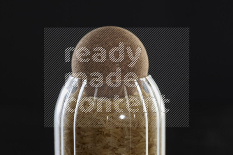 Basmati golden rice in a glass jar on black background