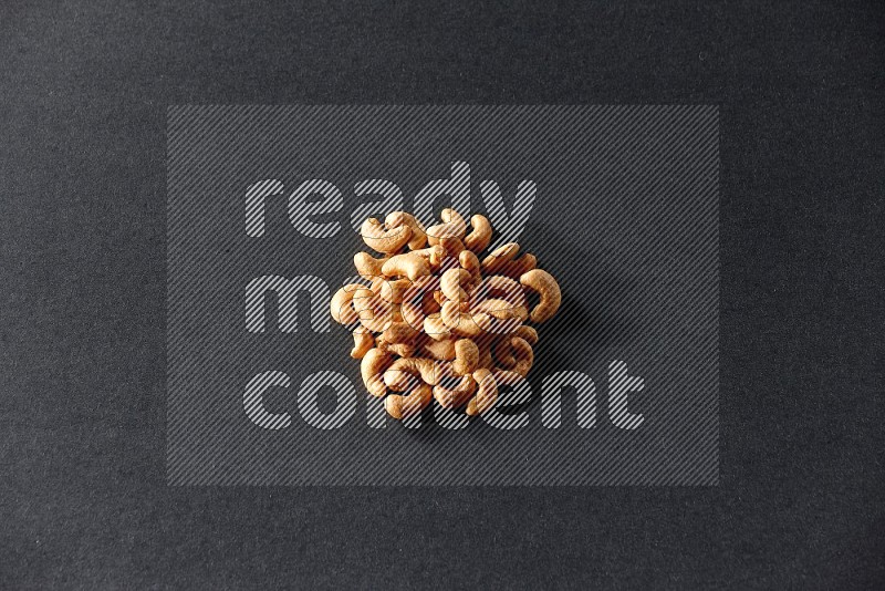 A bunch of cashews on a black background in different angles