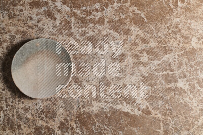 A multicolored pottery plate on beige marble background