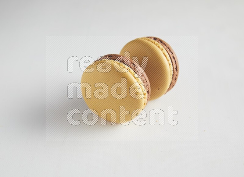 45º Shot of two Yellow and Brown Chai Latte macarons on white background