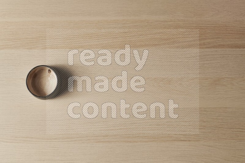 A beige pottery bowl on light wooden background