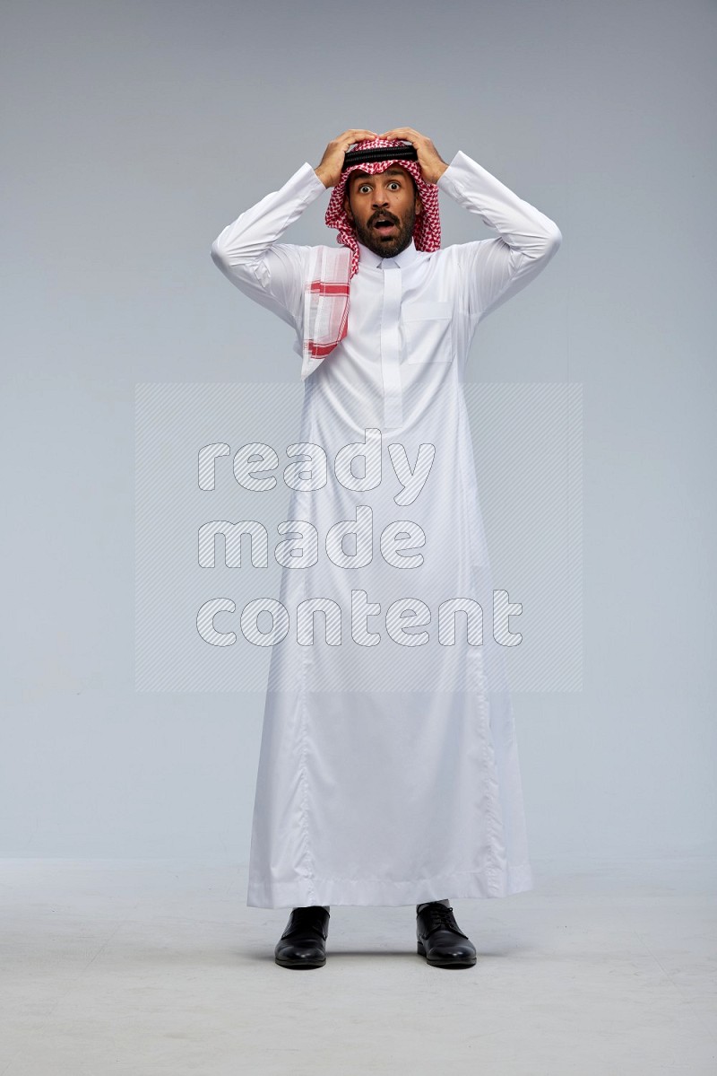 Saudi man Wearing Thob and shomag standing interacting with the camera on Gray background