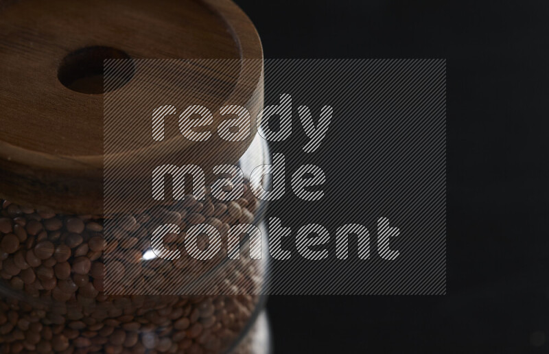 عدس بني في وعاء زجاجي على خلفية سوداء