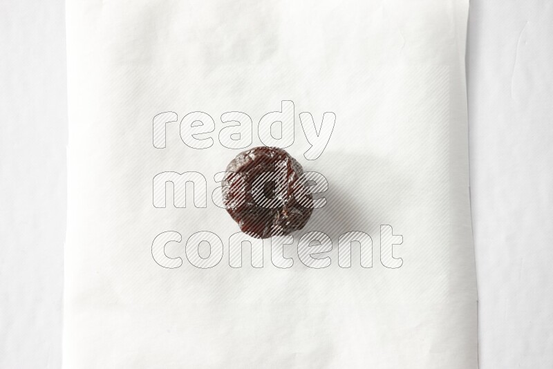 A dried plum on a piece of paper on a white background in different angles