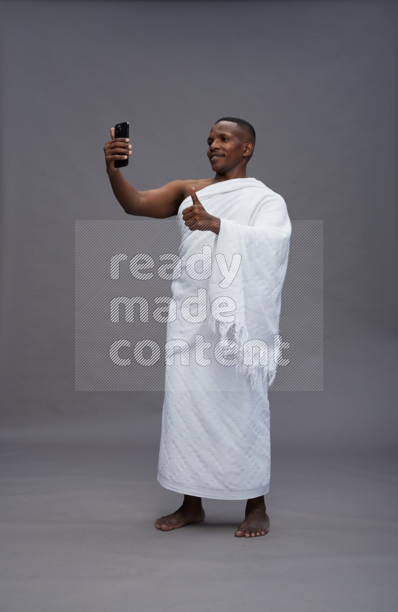 A man wearing Ehram Standing taking selfie on gray background