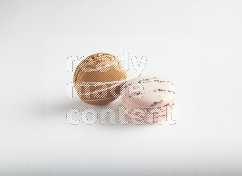 45º Shot of of two assorted Brown Irish Cream, and pink orange blossom macarons on white background