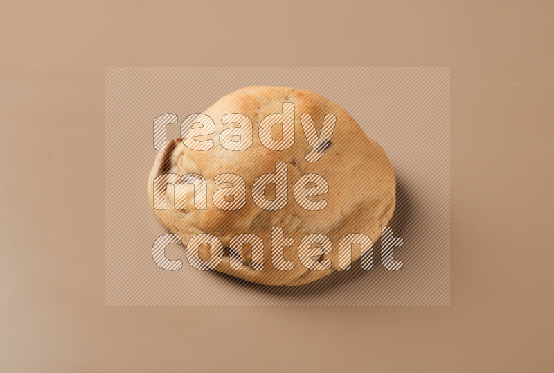 a whole chocolate chip cookie on a brown background