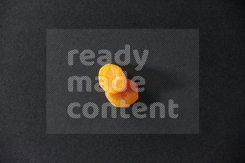 Two dried apricots on a black background in different angles