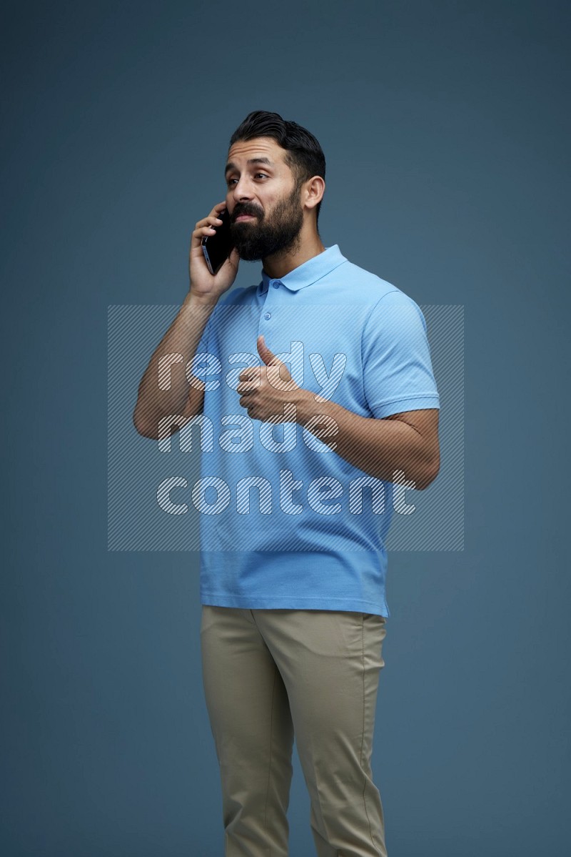 A man having a Call in a blue background wearing a Blue shirt