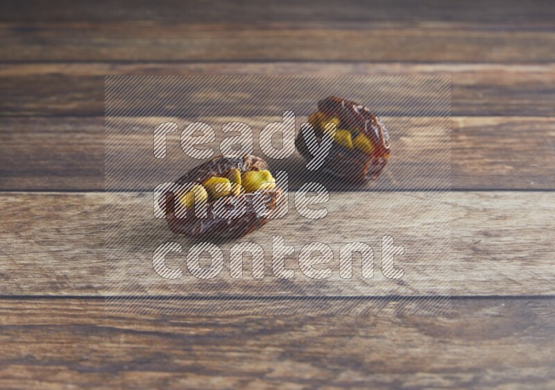 two pistachio stuffed madjoul date on a wooden background