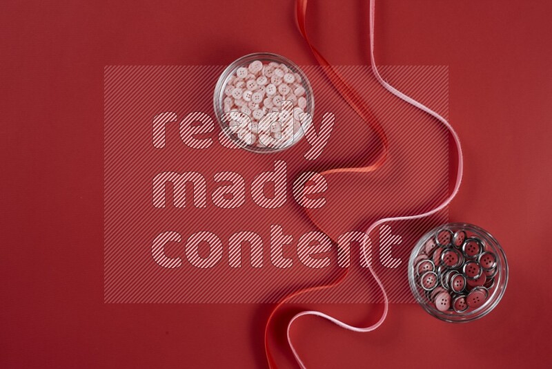 A pink and red collection of sewing and tailoring tools arranged on a red background