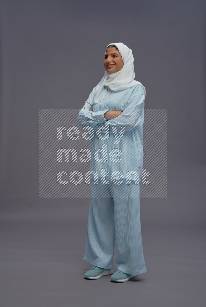 Saudi woman wearing hijab clothes standing with crossed arms on gray background