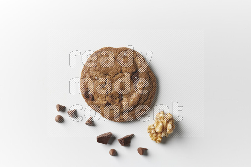 A single chocolate chips cookie with chocolate and walnuts beside it on a white background