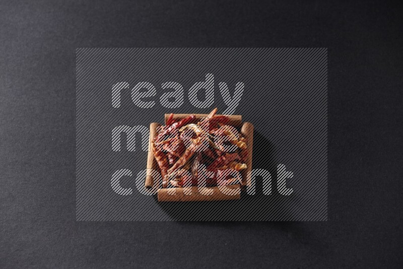 A single square of cinnamon sticks full of chilis on black flooring