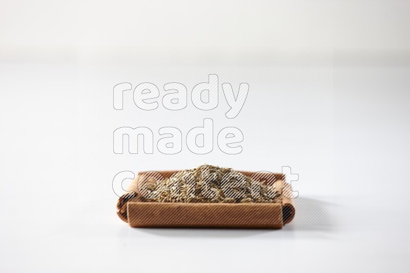 A single square of cinnamon sticks full of cumin on white flooring
