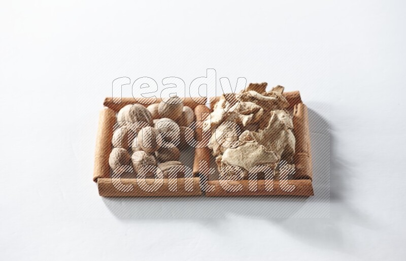 2 squares of cinnamon sticks full of dried ginger and nutmegs on white flooring