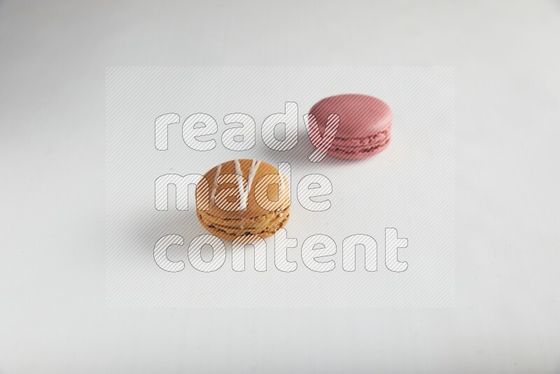 45º Shot of of two assorted Brown Irish Cream, and Pink Raspberry macarons on white background