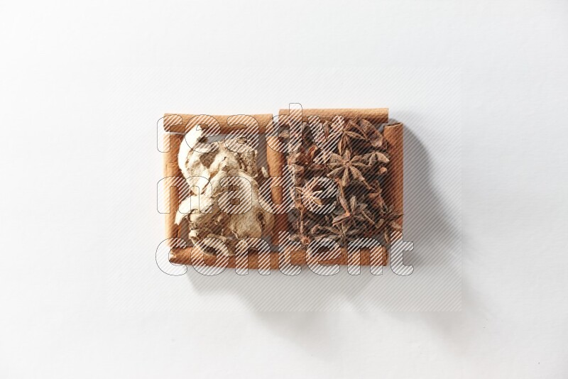 مربعان من أعواد القرفة ممتلئان باليانسون النجمي والزنجبيل المجفف علي خلفية بيضاء
